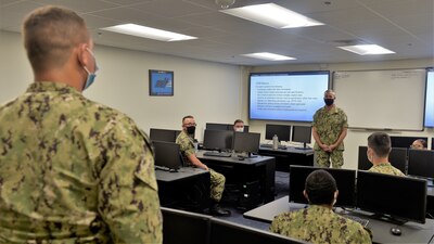 PENSACOLA, Fla. (August 20, 2020)  Rear Adm. Pete Garvin (right), commander, Naval Education and Training Command (NETC), fields a question from a student Sailor attending the Cyber Threat Emulation Course offered by Information Warfare Training Command (IWTC) Corry Station. Garvin, along with NETC Force Master Chief Matthew Harris, visited for a familiarization brief and tour of the Center for Information Warfare Training (CIWT) and IWTC Corry Station onboard Naval Air Station Pensacola Corry Station, Pensacola, Florida. The visit offered an opportunity to update them on CIWT / IWTC Corry Station training and development approaches for building a talented fleet through initiatives, such as Ready, Relevant Learning, that take recruits from "street to fleet" and transform civilians into highly skilled, operational, and combat-ready information warfare warfighters.
