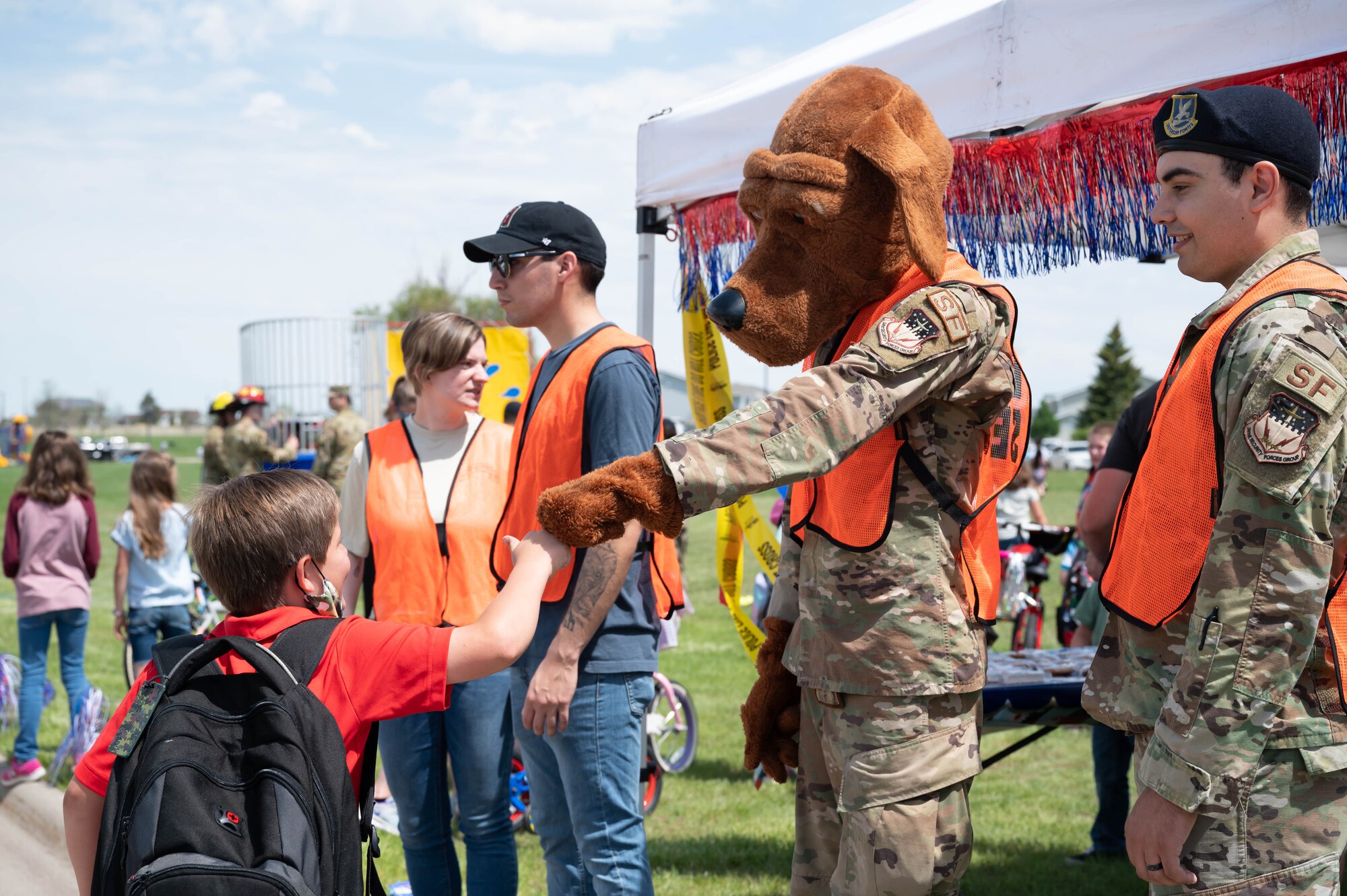 McGruff the crime dog fist bumps a military child during a bike safety rodeo June 4, 2021, at Malmstrom Air Force Base, Mont.
