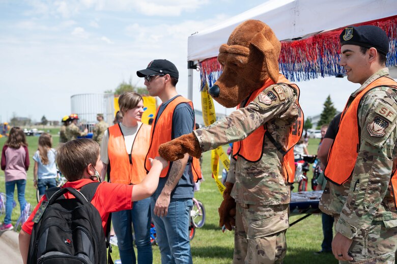 McGruff the crime dog fist bumps a military child during a bike safety rodeo June 4, 2021, at Malmstrom Air Force Base, Mont.