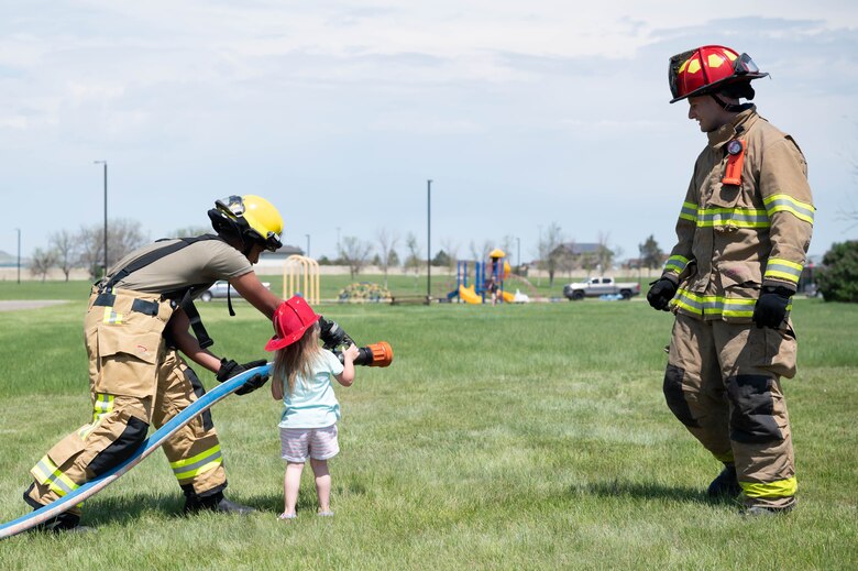 Airman 1st Class Nilton Pinto Depina, left, 341st Civil Engineer Squadron firefighter, demonstrates how to operate a fire hose during a bike safety rodeo June 4, 2021, at Malmstrom Air Force Base, Mont.