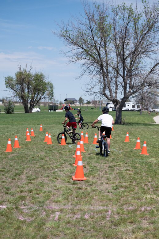Military children ride bicycles through an obstacle course during a bike safety rodeo June 4, 2021, at Malmstrom Air Force Base, Mont.