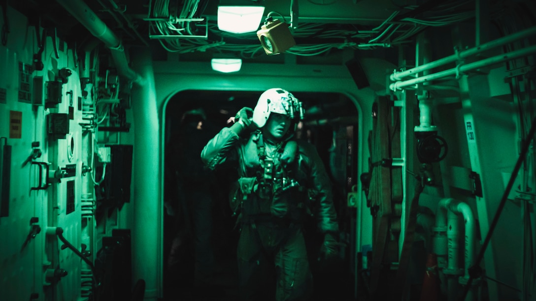 A U.S. Marine with Marine Medium Tiltrotor Squadron 165, 11th Marine Expeditionary Unit, leads Marines assigned to Alpha Company, Battalion Landing Team 1/1, 11th MEU, through a passageway aboard amphibious transport dock USS Portland to departure for a helicopter raid, May 18, 2021. Marines and Sailors of the 11th MEU and Essex Amphibious Ready Group are underway conducting integrated training off the coast of southern California.