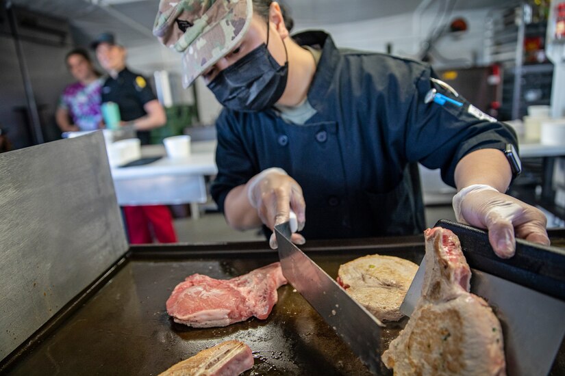 Sgt. Patricia Catacutan prepares food during a culinary demonstration by Alaska Army National Guard culinary specialists on Joint Base Elmendorf-Richardson, May 14, as part of the Alaska Army National Guard’s new Partnership for Youth Success program. The PaYS program is a strategic partnership between the Army National Guard and a cross section of private businesses, universities, and public institutions. It provides Alaska’s newest Citizen-Soldiers the opportunity to increase their prospects for potential civilian employment while serving their country. (U.S. Army National Guard photo by Edward Eagerton)