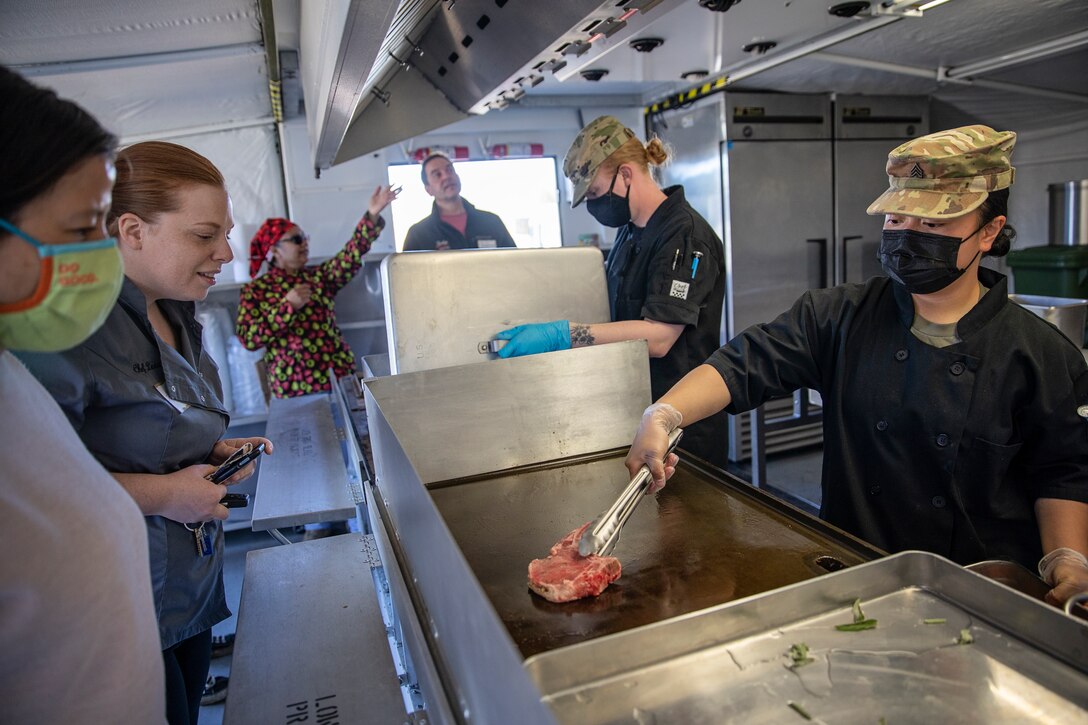 Laile Fairbairn, managing partner of Spenard Roadhouse, Snow City Cafe, South Restaurant + Coffeehouse and Crush Wine Bistro, and Lexa Gokey, chef at the Bridge Seafood Restaurant, watch a culinary demonstration by Alaska National Guard culinary specialists on Joint Base Elmendorf-Richardson, May 14. The demonstration offered local businesses a behind the scenes look at the Alaska Army National Guard culinary career field to introduce employers to the new Partnership for Youth Success program. The PaYS program is a strategic partnership between the Army National Guard and a cross section of private businesses, universities, and public institutions. It provides Alaska’s newest Citizen-Soldiers the opportunity to increase their prospects for potential civilian employment while serving their country. (U.S. Army National Guard photo by Edward Eagerton)