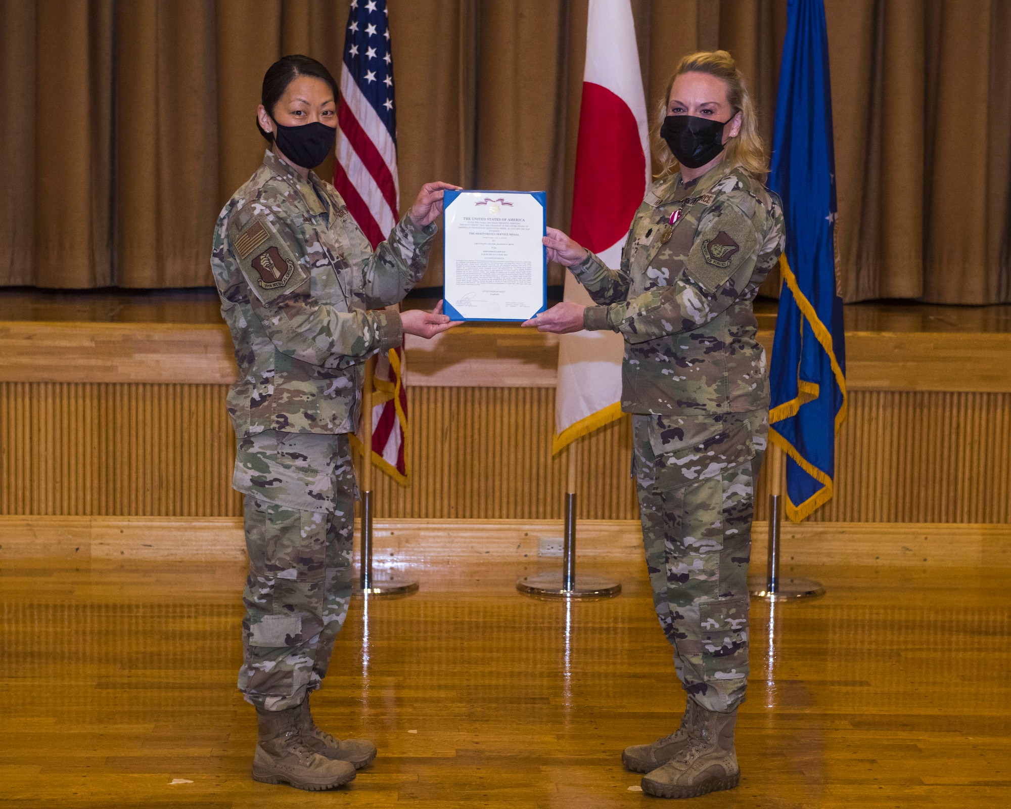 Women in uniform pose for a photo while holding a certificate.