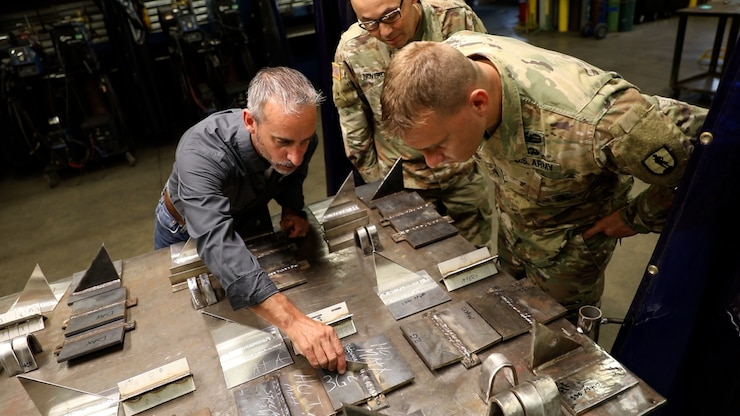 Eric Vannoy, lead welding instructor at Salina Area Technical College, left, inspects the work of Soldiers enrolled in the Advanced Leaders Course for the 91E Allied Trade Specialist military occupational specialty qualification course at the Kansas Army National Guard’s Regional Training Site for Maintenance in Salina, Kansas, May 20, 2021. The KSARNG-SATC  partnership gives Soldiers completing the Army course the opportunity to enroll in and receive credit for college courses.