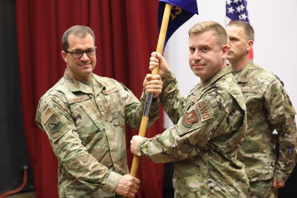 An Airman receives a guide-on from another Airman.