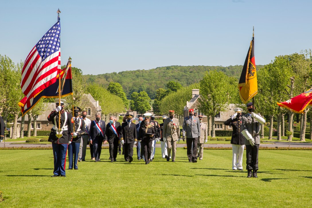 The official party members walk to their seats during a ceremony at Aisne-Marne American Cemetery in Belleau, France, May 30, 2021. The ceremony was held Memorial Day weekend in commemoration of the 103rd anniversary of the battle of Belleau Wood, conducted to honor the legacy of service members who gave their lives in defense of the United States and European allies.  U.S. Marines and Sailors from Marine Corps Forces Europe and Africa, 5th Marine Regiment, 6th Marine Regiment, 1st Marine Division band, U.S. Soldiers from the Army 26th Infantry Division, 2nd Infantry Division representatives, German and French service members, and local officials participated in the ceremony. The joint color guard included the U.S. Army colors, a first for the historic ceremony. This was the first time since the battle over a century ago that U.S. Marine Corps, U.S. Army, U.S. Navy, French, and German service members were all present for the ceremonies.  (U.S. Marine Corps photo by Staff Sgt. Brytani Musick)
