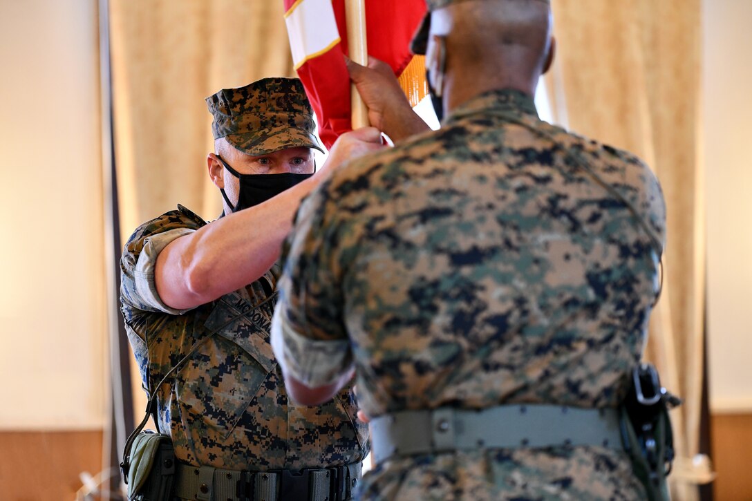 U.S. Marine Corps Sgt. Maj. Aaron G. McDonald, command sergeant major of U.S. Marine Corps Forces, Europe and Africa (MARFOREUR/AF), hands the organizational colors to outgoing commander Maj. Gen. Michael E. Langley during the MARFOREUR/AF change of command ceremony at the U.S. Army Garrison Stuttgart firehouse in Boeblingen, Germany, May 6, 2021. (U.S. Army Photo by Jason Johnston)