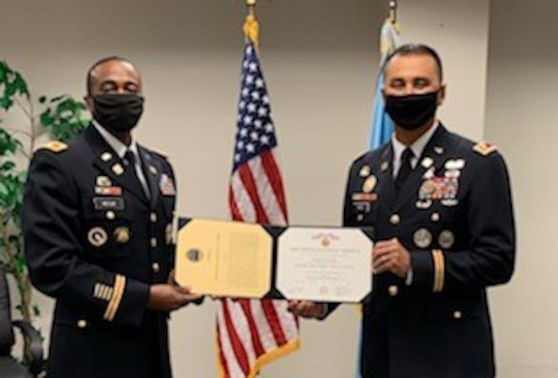 two military officers stand in uniform holding a certificate