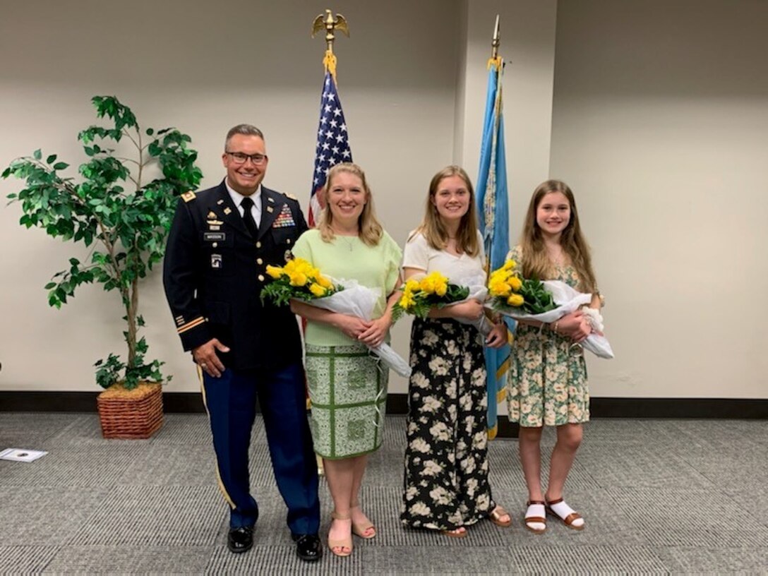 A military officer in uniform stands with his family