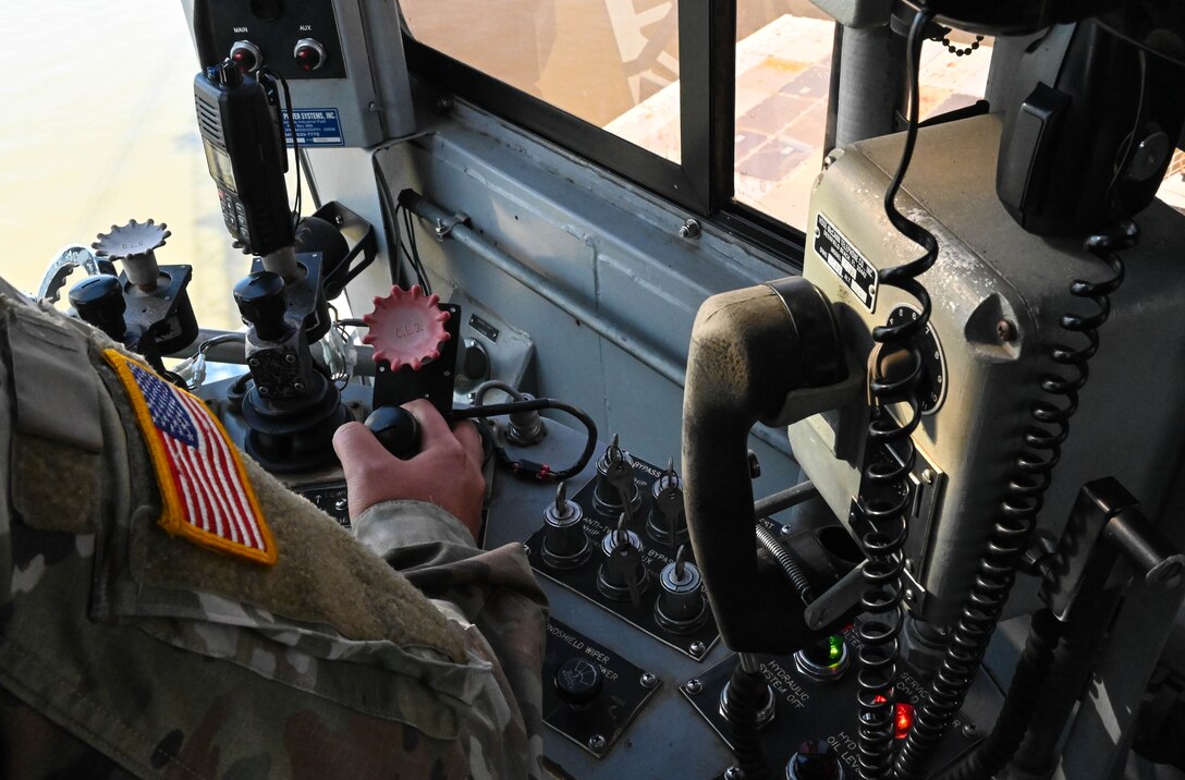 A U.S. Soldier from the 7th Transportation Brigade (Expeditionary) operates a crane at 3rd Port, Joint Base Langley-Eustis, Virginia, March 9, 2021. Utilizing the crane, a barge of supplies and equipment was loaded and shipped to Naval Station Norfolk for upcoming deployments. (U.S. Air Force photo by Senior Airman Sarah Dowe)
