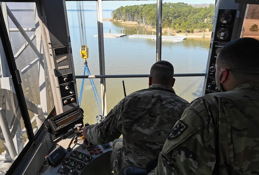 A U.S. Soldier from the 7th Transportation Brigade (Expeditionary) operates a crane at 3rd Port, Joint Base Langley-Eustis, Virginia, March 9, 2021. Utilizing the crane, a barge of supplies and equipment was loaded and shipped to Naval Station Norfolk for upcoming deployments. (U.S. Air Force photo by Senior Airman Sarah Dowe)