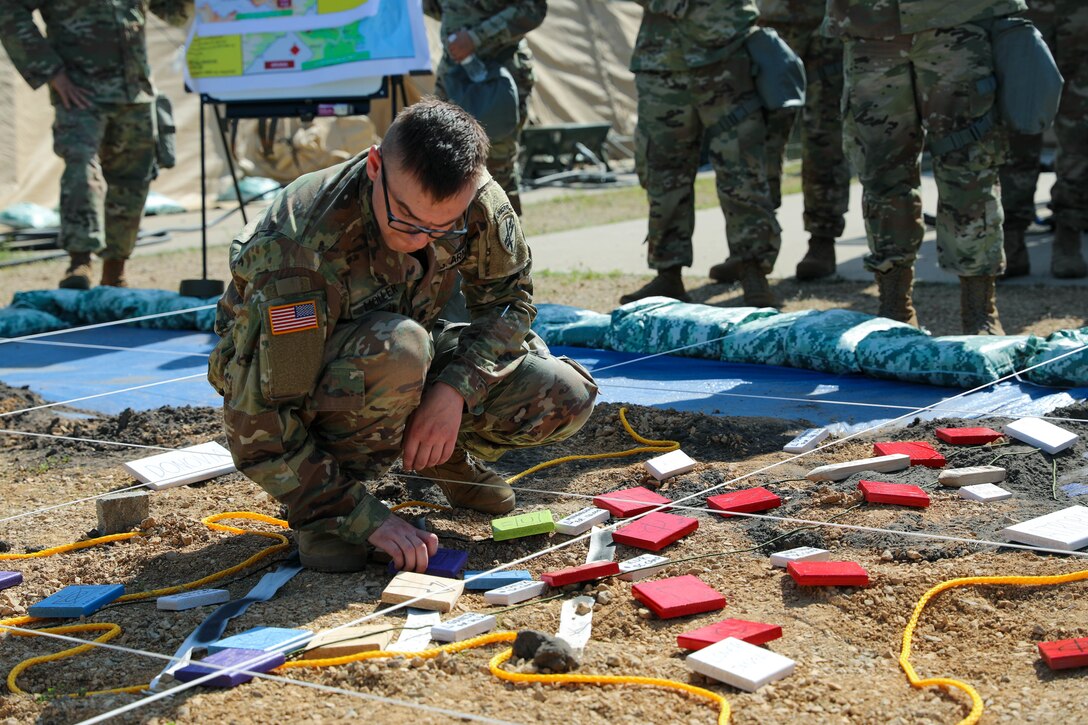 U.S. Army Reserve Spec. Kyle Moller, a civil affairs specialist from the 364th Civil Affairs Brigade, moves markers representing units into position as the next phase of battle is explained during the rehearsal of concept brief at Command Post Exercise – Functional (CPX-F) 21-02 at Ft. McCoy, Wis., on June 5, 2021. Units from across U.S. Army Civil Affairs and Psychological Operations Command (Airborne) are working together at Ft. McCoy to improve readiness and staff interoperability in support of the U.S. Army Reserve’s mission of a globally responsive force ready to deploy at a moment's notice.