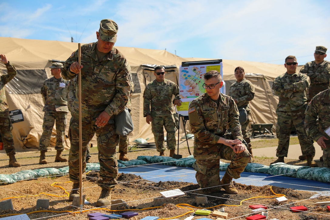 U.S. Army Reserve Maj. Richard Flores, 358th Civil Affairs Brigade, gets an assist from Spec. Kyle Moller, a Civil Affairs Specialist with the 364th Civil Affairs Brigade and augmentee to the exercise S2 section as they brief the change in phases during the rehearsal of concept brief at Command Post Exercise – Functional (CPX-F) 21-02, June 5, 2021, at Ft. McCoy, Wis. CPX-F brings units from across the command together to work in cooperation in an exercise scenario that mirrors real-world mission concerns.