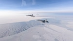 U.S. Air Force F-16s, Royal Canadian Air Force CF-18, and U.S. Air Force F-22 join up with a U.S. Air Force B-52 Stratofortress fly over an area near the Beaufort Sea.