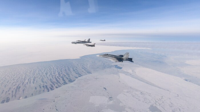 U.S. Air Force F-16s, Royal Canadian Air Force CF-18, and U.S. Air Force F-22 join up with a U.S. Air Force B-52 Stratofortress fly over an area near the Beaufort Sea.