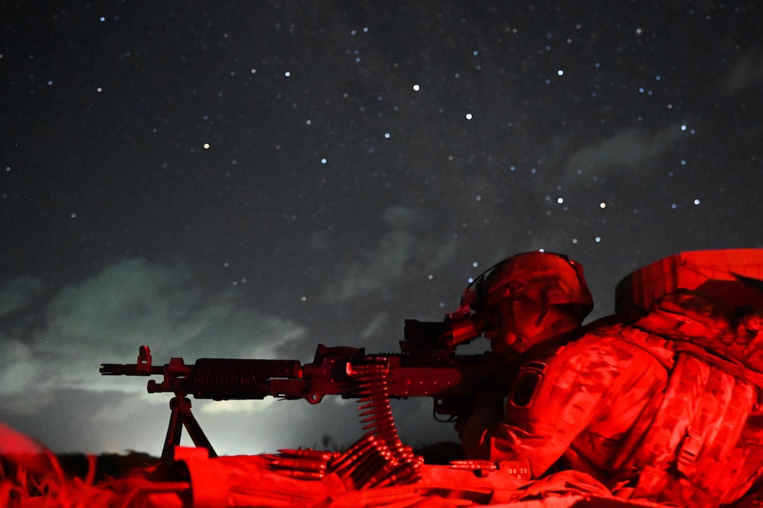 A soldier aims a weapon under a starry night sky.