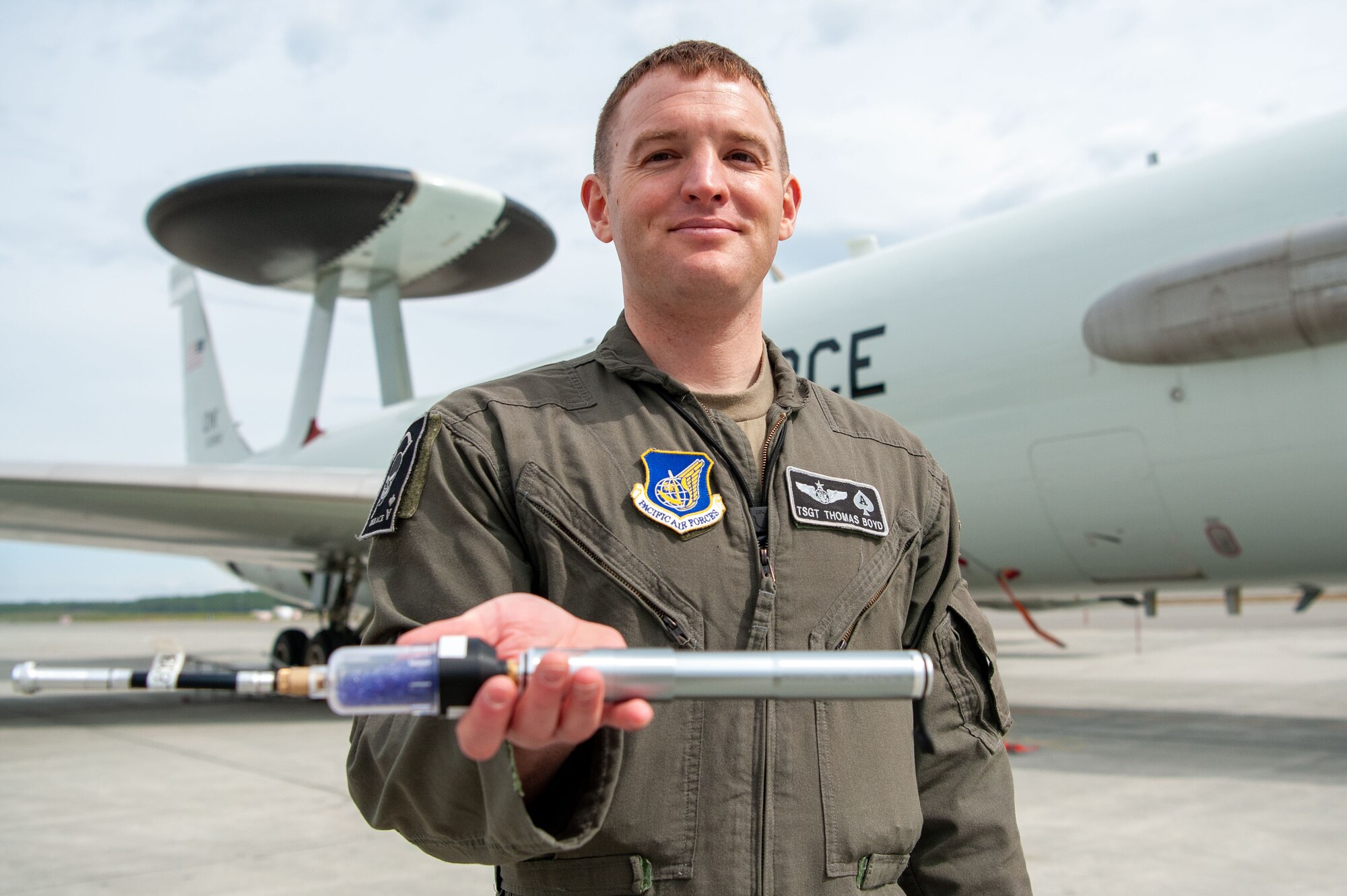 U.S. Air Force Tech. Sgt. Thomas Boyd, the 3rd Wing noncommissioned officer in charge of Agile Combat Employment, poses for a photo holding his solution to the radio deficiency in the E-3 Sentry Airborne Warning and Control System (AWACS) aircraft at Joint Base Elmendorf-Richardson, Alaska, May 27, 2021. The pump created increases the AWACS’ communications capabilities in the air, and reduces the amount of equipment that aircrew and maintenance are required to carry to and from the aircraft.