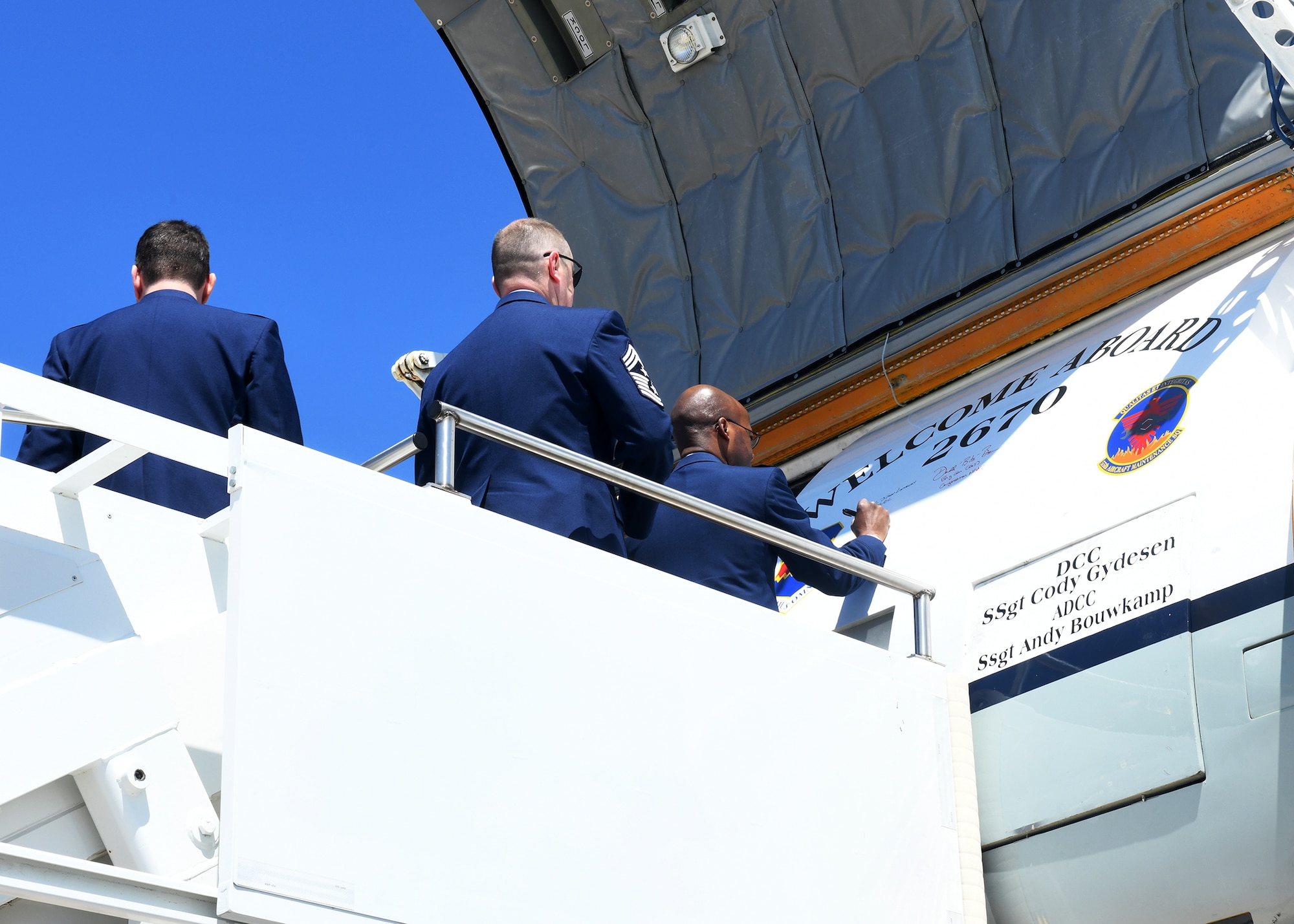 Man in Air Force uniform signing the side of an aircraft.