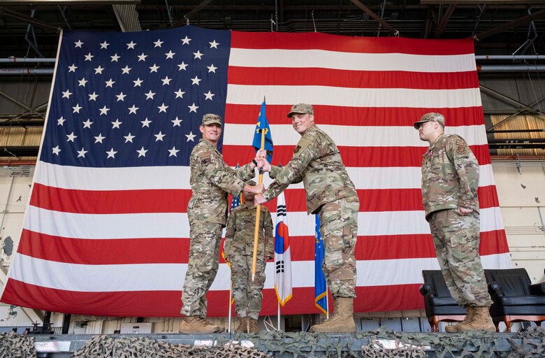 Two commanders pose for a photo during a ceremony.