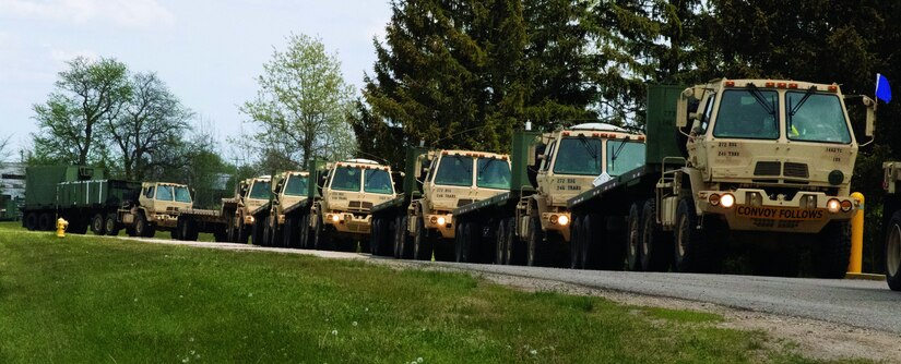 A row of military vehicles drives on a road.