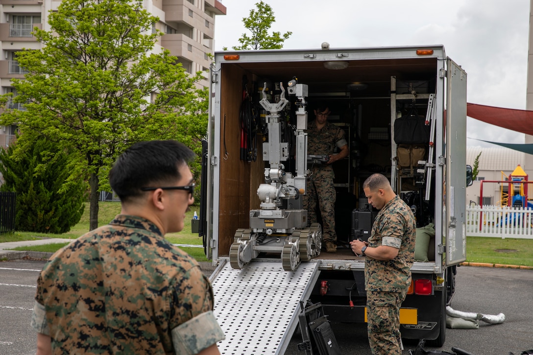 U.S. Marine Corps Staff Sgt. Kevin Syphanthavong, (left), Sgt. Anthony Negrete, (center), and Staff Sgt. Jake Castro, (right), Explosive Ordnance Disposal technicians with Marine Corps Air Station Iwakuni EOD, unload an EOD robot for an exercise aboard MCAS Iwakuni, Japan, May 19, 2021. This particular exercise was designed to allow EOD to utilize a robot in their arsenal, which allows them to engage explosives at a greater distance with no harm to Marines.