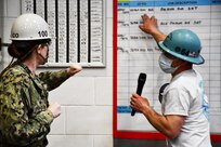 Norfolk Naval Shipyard (NNSY) Shop 64 Woodcrafter Dean Vaughn, Jr. discusses the shop’s new crew boards with Shipyard Commander Captain Dianna Wolfson, which provide consistency and standardization to shop assignments through updated information such as job descriptions, locations, responsible persons and start and completion dates.