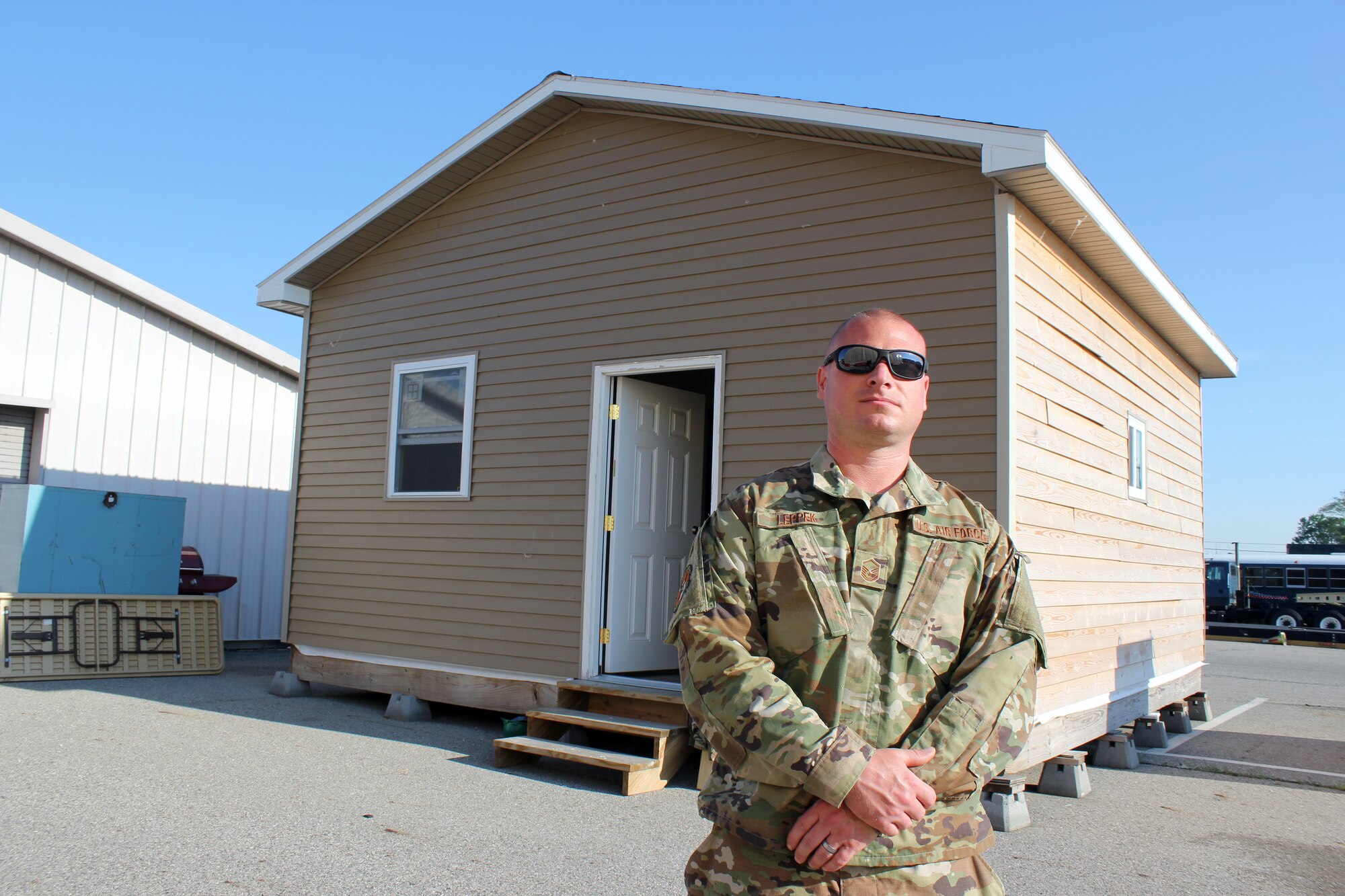 Master Sgt. Derek Leppek stands outside a small B-Hut, or barracks hut, style building at Selfridge Air National Guard Base, Mich., June 6, 2021. Leppek oversaw the creation of the temporary building, which will be used by the 127th Civil Engineer Squadron for hands-on construction trades training at the base. (U.S. Air Force photo by Master Sgt. Dan Heaton)