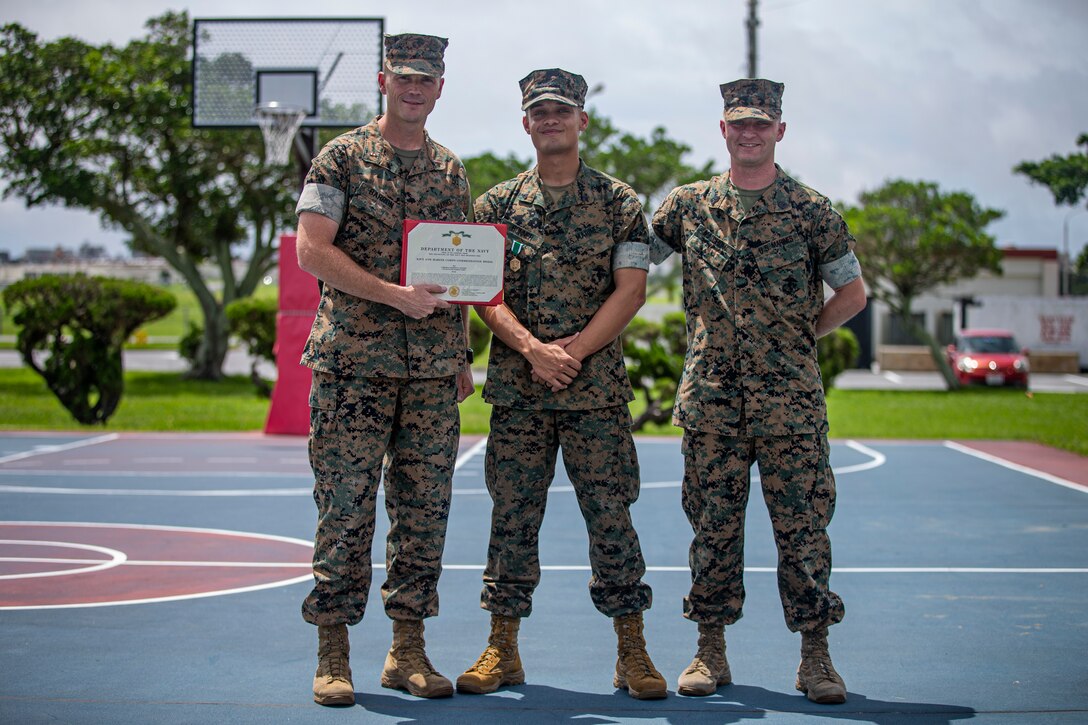 U.S. Marine Corps Chief Warrant Officer 4 Benjamin Barron, the chemical, biological, radiological, and nuclear defense officer with the 1st Marine Aircraft Wing, Cpl. Dominick Bonner, a CBRN defense specialist, and Gunnery Sgt. Joshua Malchow, the CBRN defense operations coordinator, pose for a group photo on Marine Corps Air Station Futenma, Okinawa, Japan, June 8, 2021. Bonner, a native of Parkville, Maryland, was enjoying breakfast at a restaurant to celebrate his wife’s birthday when he was made aware of a restaurant employee who required medical attention. After entering the kitchen area and locating the man, lying motionless without a pulse, Bonner laid the man on his back and began chest compressions, taking over for a fatigued employee. Bonner continued to provide lifesaving aid for over ten minutes, sustaining the man’s life, until relieved by Japanese paramedics who evacuated the man to a local medical facility.