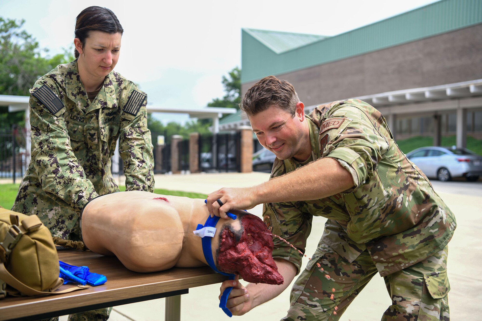 Hospital Corpsman 1st Class Alichia Long (left) assists Capt. Adam Fannin, 445th Aerospace Medicine Squadron, on the application of a tourniquet on a training dummy during Tactical Combat Casualty Care (TCCC) training at Burke County High School here June 8, 2021. TCCC is developed by the Department of Defense’s Defense Health Agency Joint Trauma System to teach evidence-based, life-saving techniques and strategies for providing the best trauma care on the battlefield.