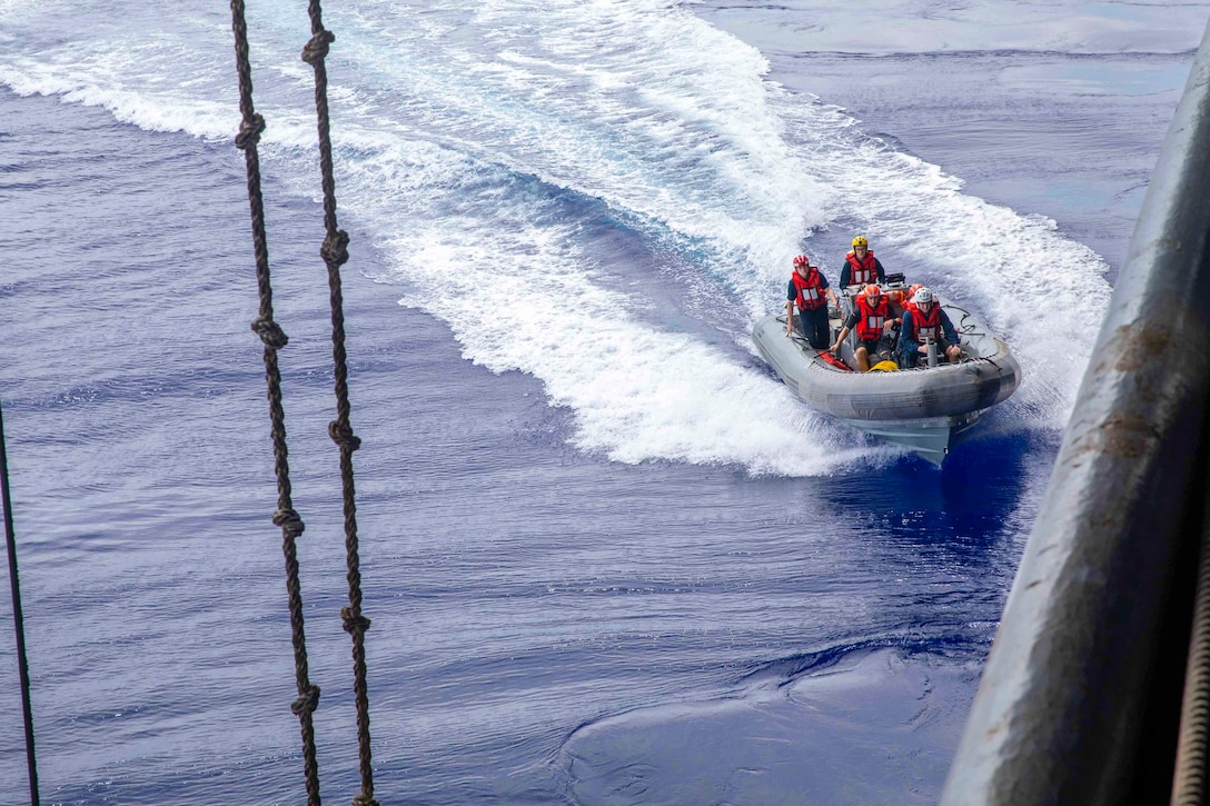 Sailors travel through waters in a small inflatable boat.