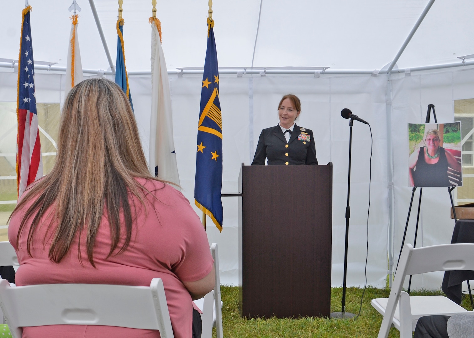 A Navy admiral speaks to listeners inside of a white tent.