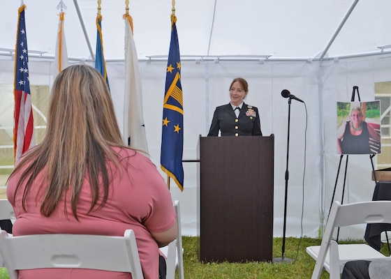 A Navy admiral speaks to listeners inside of a white tent.