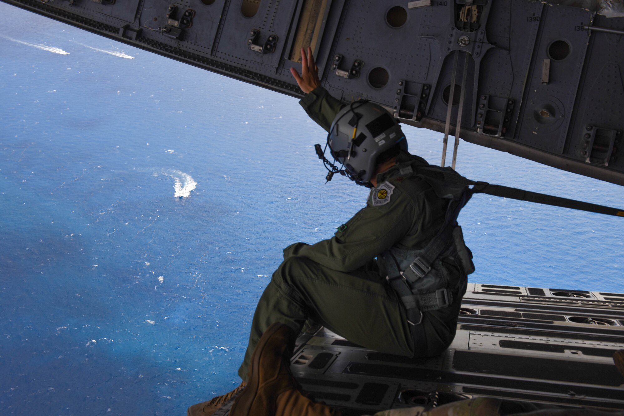 U.S. Air Force Maj. Mack Delgado, C-17 West Coast Demo Team pilot, waves to boats off the coast of Miami Beach, Florida, from the cargo ramp of a C-17 Globemaster III, May 31, 2021. The C-17 was headed back to Joint Base Lewis-McChord, Washington, after completing their demonstrations in the National Salute to Our Heroes Hyundai Air and Sea Show. (U.S. Air Force photo by Senior Airman Mikayla Heineck)