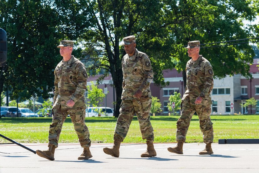 three men walking wearing army uniforms.