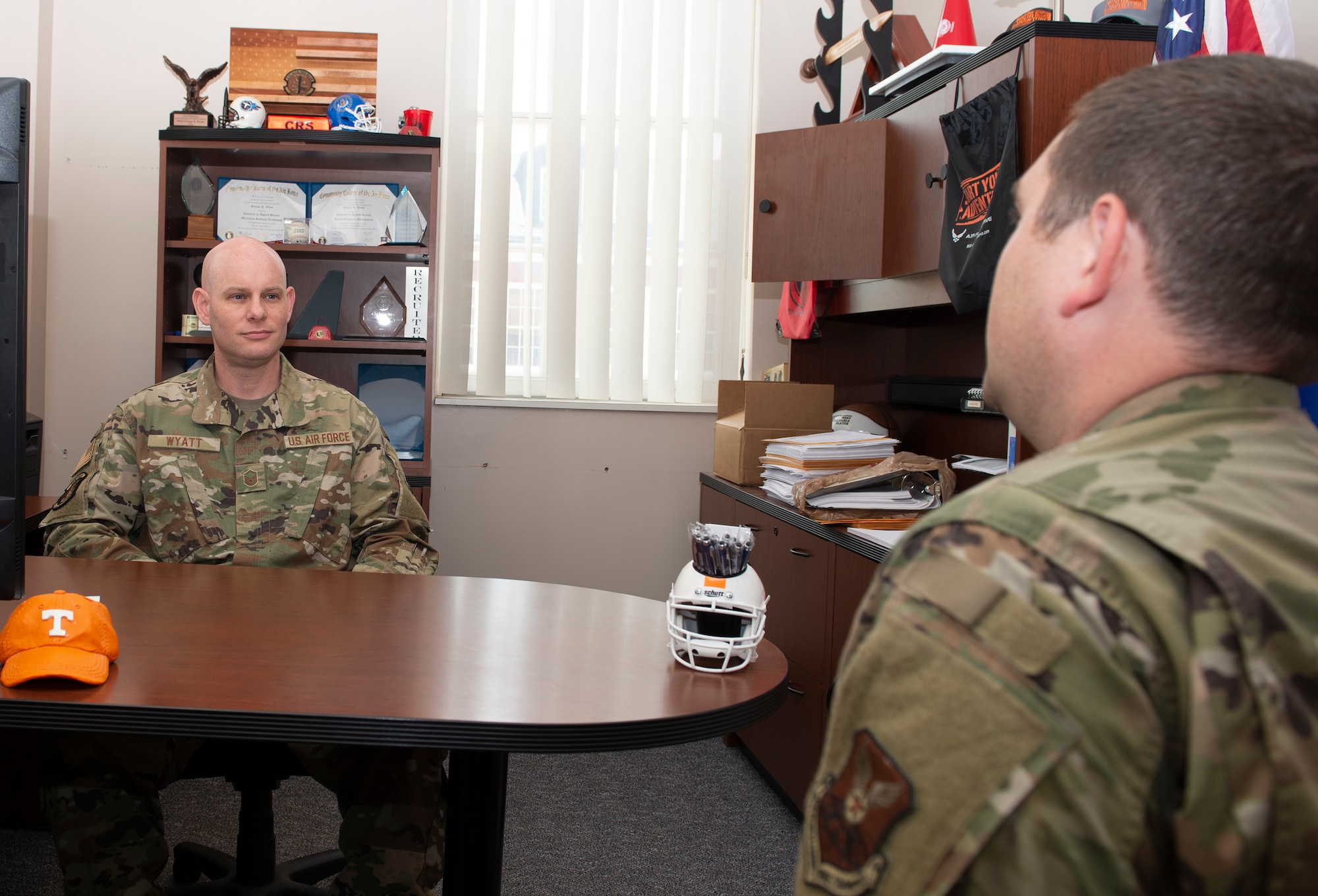 Master Sergeant sitting behind a desk in his office, listening to Airmen seated in front of the desk