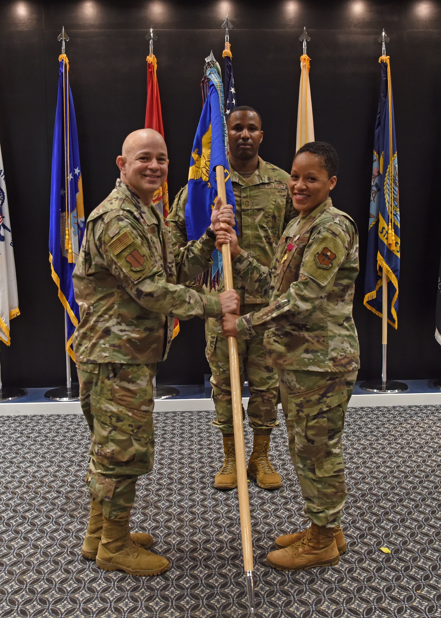 U.S. Air Force Col. Lauren Byrd, 17th Medical Group outgoing commander, passes the17th MDG guidon to Col. Andres Nazario, 17th Training Wing commander, during the change of command ceremony at the Event Center on Goodfellow Air Force Base, Texas, June 8, 2021. Byrd led over 200 military, civilian and contract employees to serve thousands of beneficiaries and students in healthcare missions during her two years of service at Goodfellow. (U.S. Air Force photo by Senior Airman Abbey Rieves)