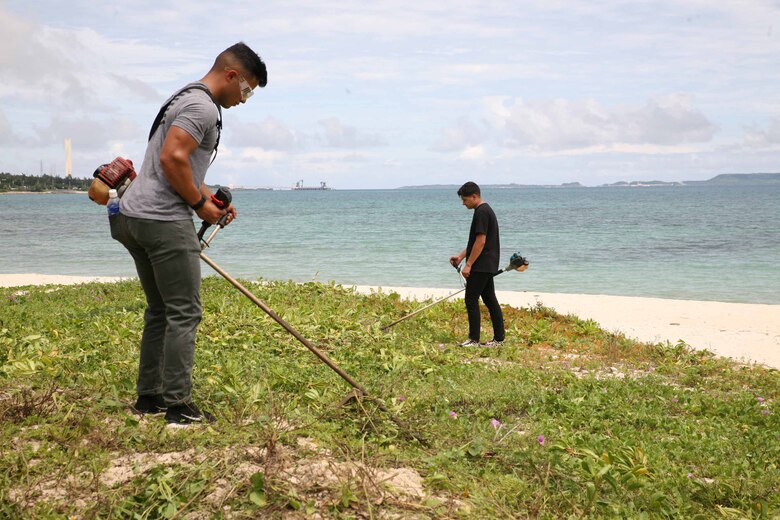伊芸海浜公園で、浜辺に生えている雑草を草刈り機で刈る海兵隊員、沖縄県金武町、２０２１年６月９日