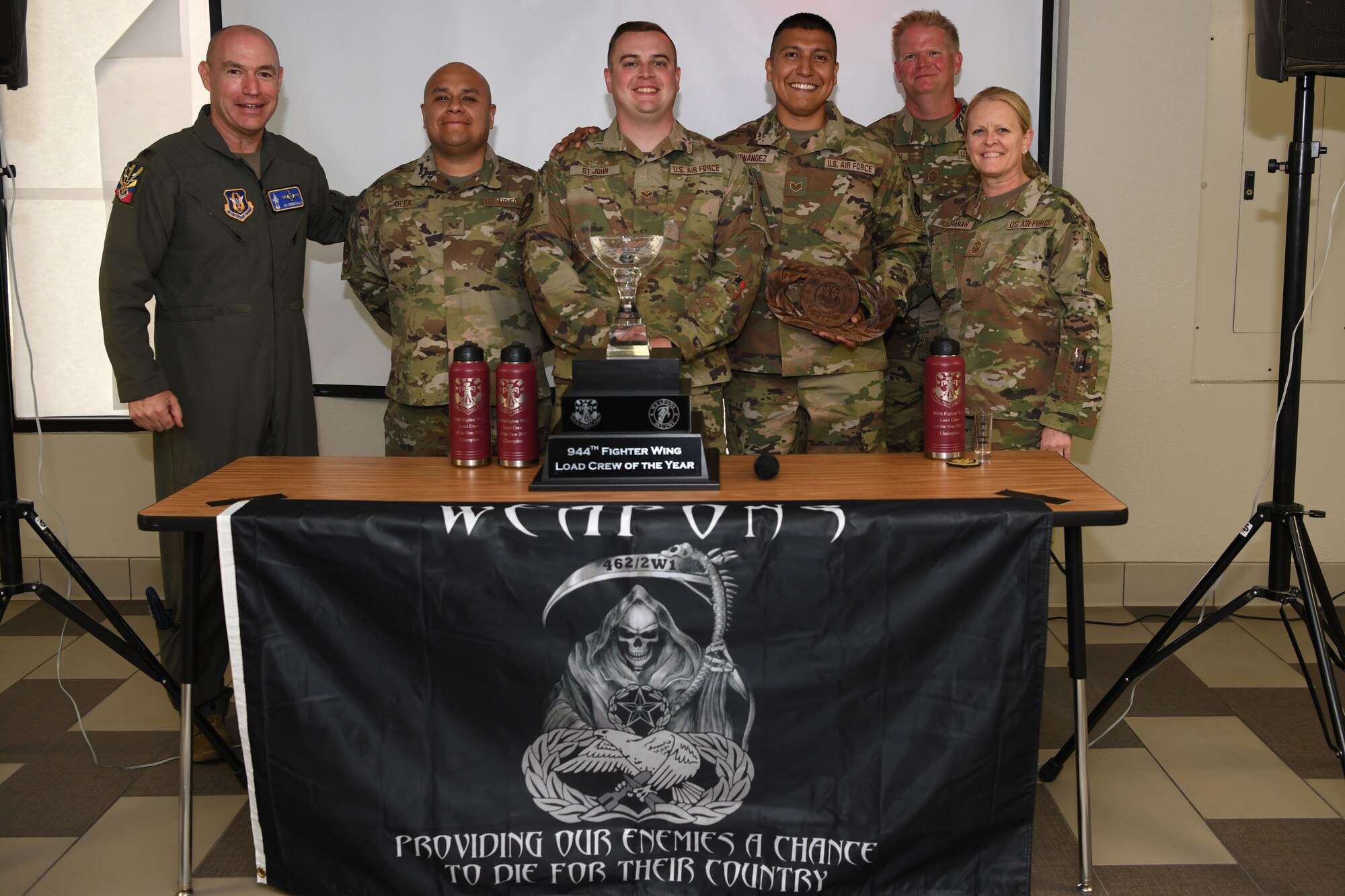 Col (ret) Jim Greenwald, former 944th Fighter Wing commander, Chief Master Sgt. Catherine Buchannan, 944th FW command chief, and Chief Master Sgt. Ralph Thompson, 944th Maintenance Squadron weapons manager, pose for a photo with the winners of the first-ever four-ship load crew competition at Luke Air Force Base, Arizona, June 5, 2021. 944th Aircraft Maintenance Squadron F-16 Fighting Falcon weapons load crew members Senior Airman Jonathan Olea and Staff Sgt.’s Riley St. John and Alberto Hernandez had a zero safety, perfect load during the competition. Out of 1,000 possible points they earned 1,062.