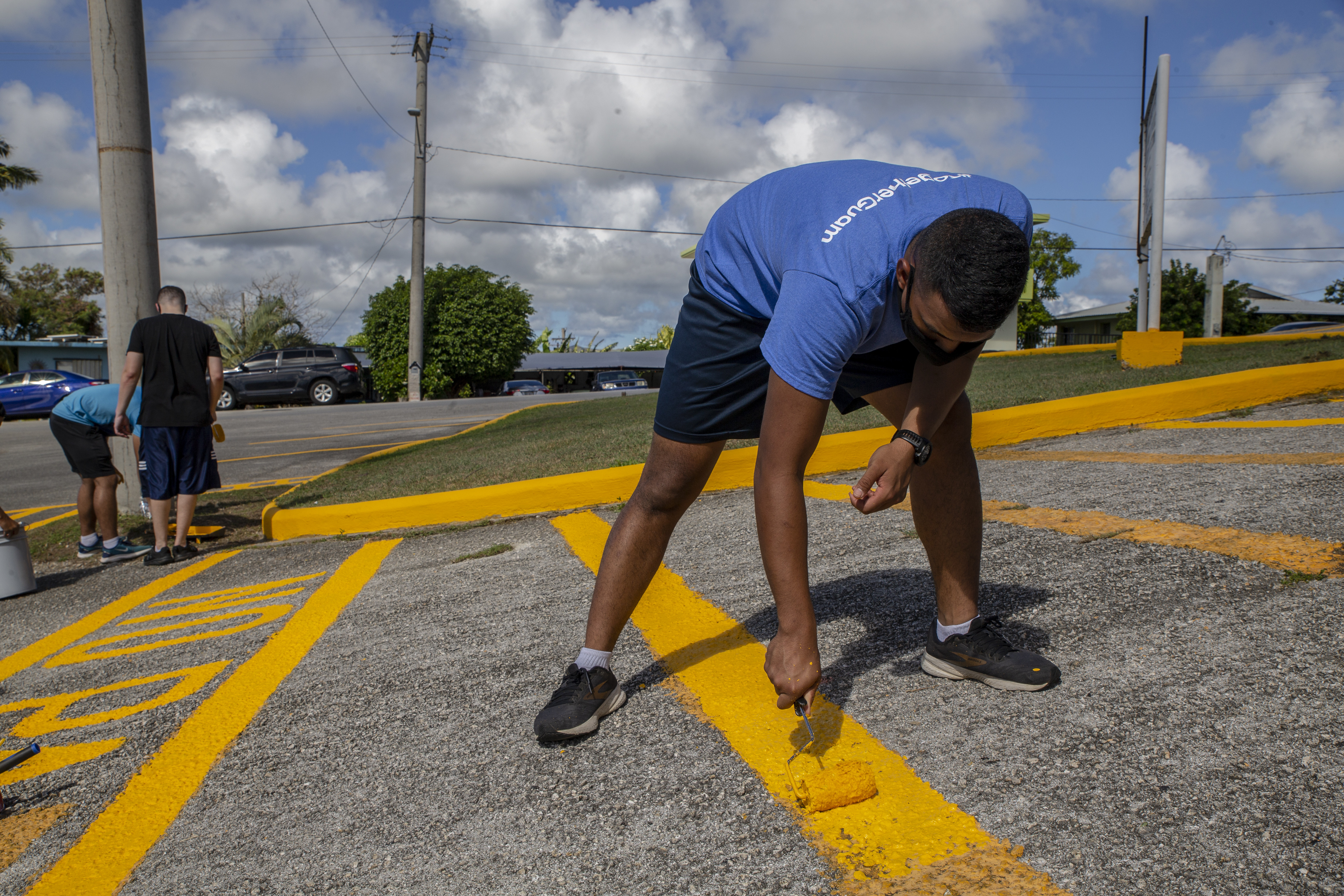 Cpl. Benajamin Ooka, a network administrator assigned to Marine Corps Base (MCB) Camp Blaz, paints a parking line during a volunteer event with employees of the Barrigada Mayor’s Office in Barrigada, Guam, April 8, 2021.