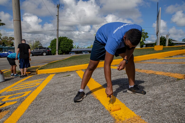 Cpl. Benajamin Ooka, a network administrator assigned to Marine Corps Base (MCB) Camp Blaz, paints a parking line during a volunteer event with employees of the Barrigada Mayor’s Office in Barrigada, Guam, April 8, 2021.