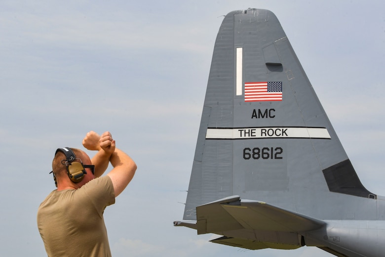 An Airman from the 354th Aircraft Maintenance Unit signals a U.S. Air Force C-130J Super Hercules from the 19th Airlift Wing to halt