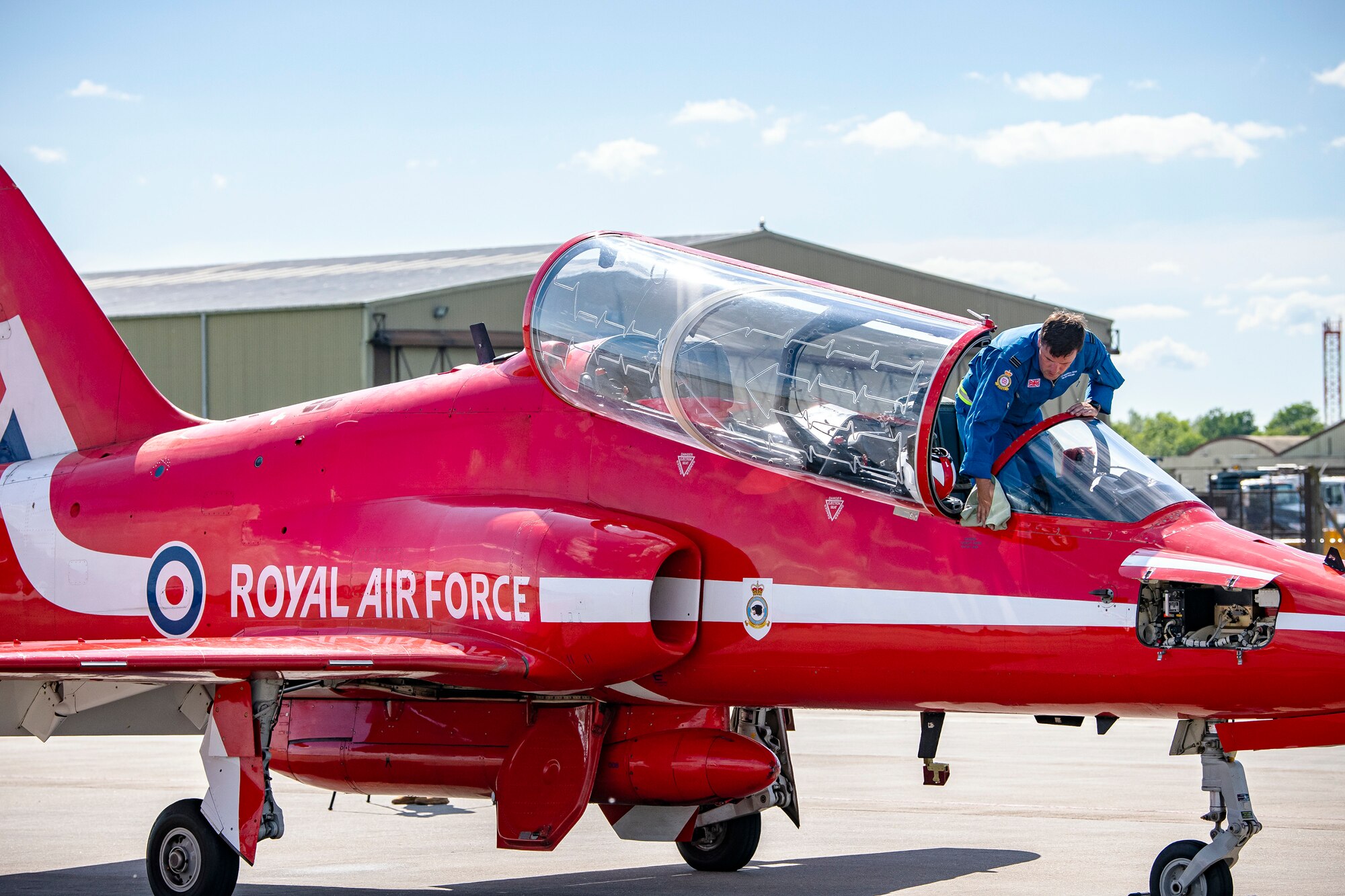 Flight Lieutenant Joe Fallon, Red Arrows Junior Engineering officer, wipes down a Hawk T1 aircraft at RAF Fairford, England, June 4, 2021. The Red Arrows landed at Fairford to refuel in preparation for the Midlands Air Festival. (U.S. Air Force photo by Senior Airman Eugene Oliver)