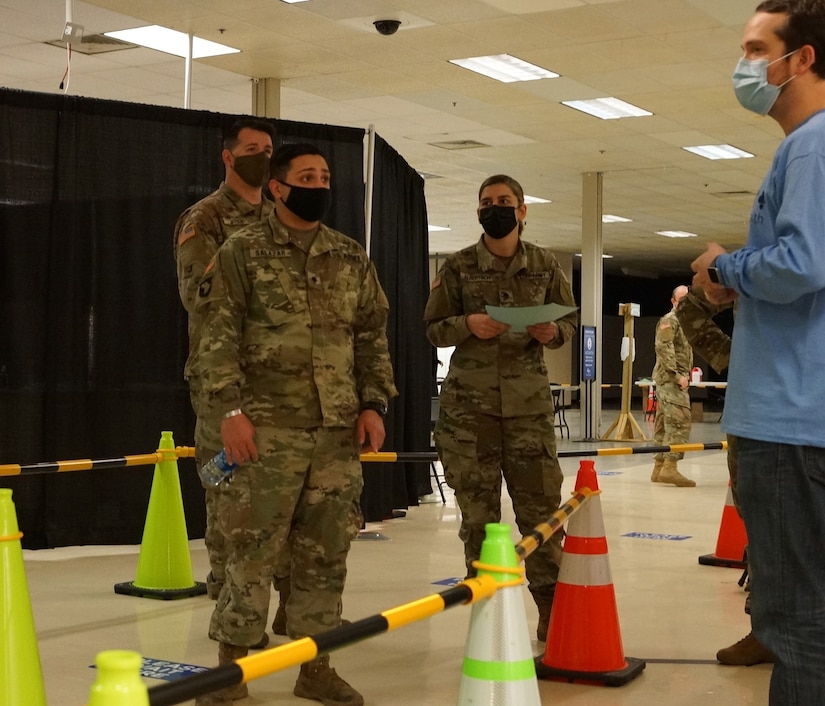 Kentucky Army National Guard Spc. Paulo Salazar with the 101st Main Command Post Operational Detachment, 75th Troop Command, coordinates with a civilian staff member from Med Center Health during the COVID-19 vaccine rollout in Bowling Green, Ky., March 6, 2021. Soldiers from across Kentucky are assisting with vaccine rollouts in Bowling Green, Lexington, and Louisville. (U.S. Army National Guard photo by Staff Sgt. Paul Glover)