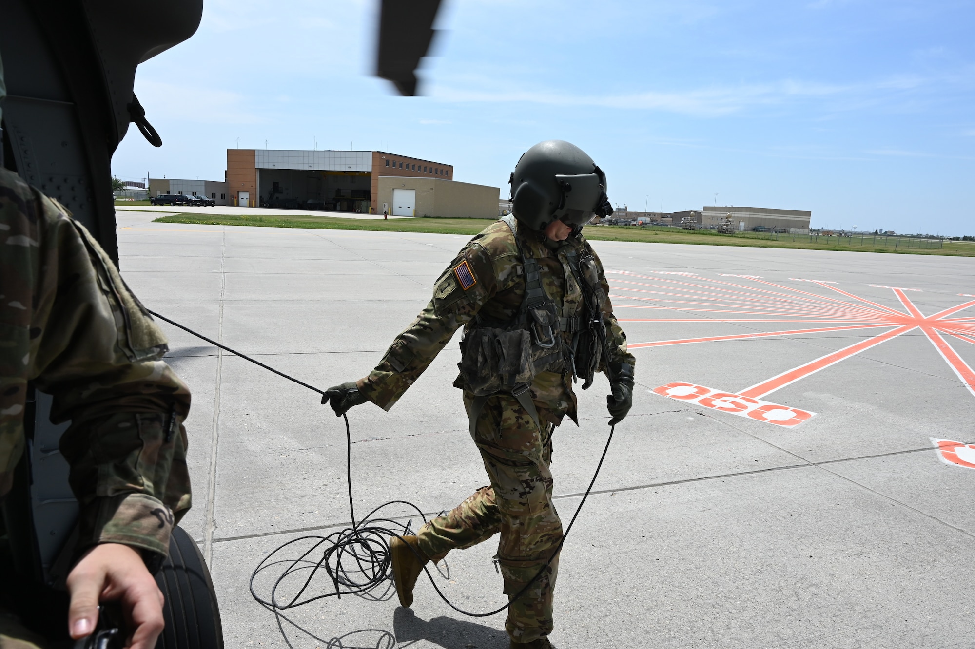 Staff Sgt. Andrew Iverson, a crew chief in the 1st Battalion, 112th Aviation Regiment, North Dakota Army National Guard, works around a UH-60 helicopter as it lands at the North Dakota Air National Guard Base, Fargo, N.D., June 8, 2021. Airmen aboard the helicopter are simulating arrival at a high-threat area for training. (U.S. Air National Guard photo by Chief Master Sgt. David H. Lipp)