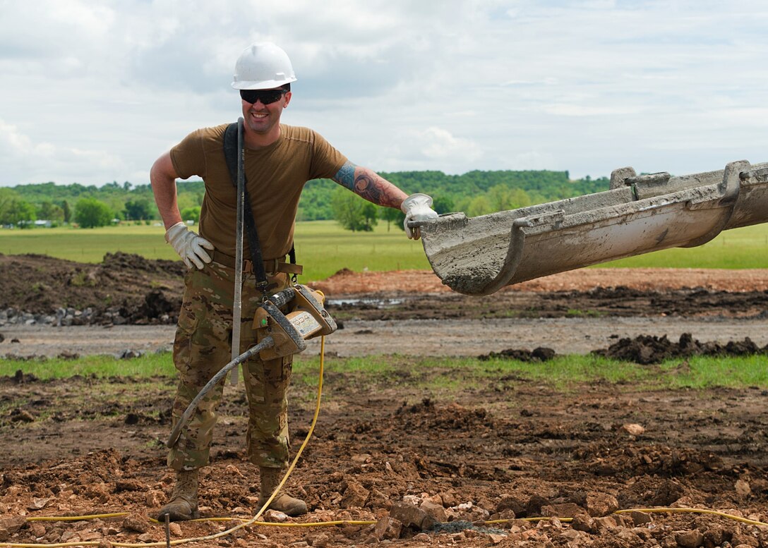 Senior Airman Ryan Pickett, with the 176th Wing’s Civil Engineer Squadron Fire and Emergency Services Flight, smiles with excitement as he finishes pouring 18 cubic yards of concrete on home site number six while participating in the Cherokee Veterans Housing Initiative in Tahlequah, Oklahoma, May 24, 2021. The initiative is a collaboration between the Department of Defense’s Innovative Readiness Training program and the Cherokee Nation that constructs new single-family homes and supporting infrastructure for eligible Cherokee Nation veterans and their families. (U.S. Air Guard photo by Staff Sgt. Clay Cook)