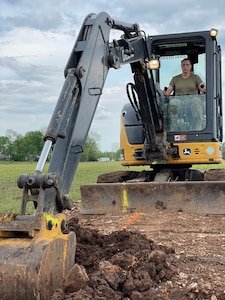Tech. Sgt. Katie Cramer, with the 176th Wing’s Civil Engineer Squadron Heavy Equipment Shop, digs a trench with a mini-excavator in preparation for pouring concrete footers on home site six while participating in the Cherokee Veterans Housing Initiative in Tahlequah, Oklahoma, May 26, 2021. The initiative is a collaboration between the Department of Defense’s Innovative Readiness Training program and the Cherokee Nation that constructs new single-family homes and supporting infrastructure for eligible Cherokee Nation veterans and their families.  (U.S. Air Guard photo by Senior Master Sgt. Michael Keegan)