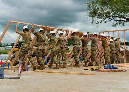 Airmen from all trades, with the 176th Wing’s Civil Engineer Squadron, raise the second exterior wall in unison as they construct the first home in the Cherokee Veterans Housing Initiative in Tahlequah, Oklahoma, May 18, 2021. The initiative is a collaboration between the Department of Defense’s Innovative Readiness Training program and the Cherokee Nation that constructs new single-family homes and supporting infrastructure for eligible Cherokee Nation veterans and their families. (U.S. Air Guard photo by Staff Sgt. Clay Cook)