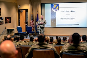 Photo of a man standing on a stage in front of an audience.